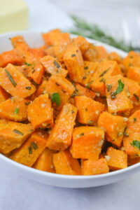 A white bowl of savory roasted sweet potatoes with rosemary.