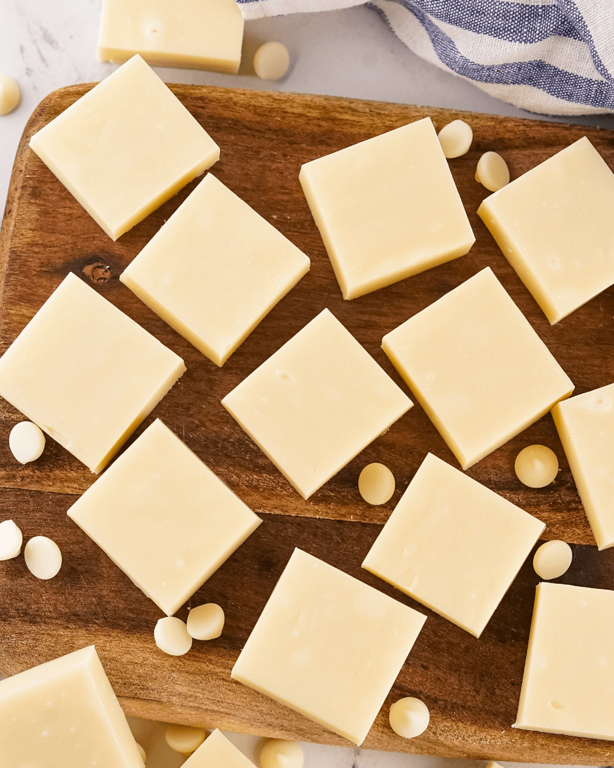 A cutting board of the squares of vanilla fudge.