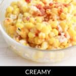 A glass bowl brimming with creamy corn casserole, finished with a generous topping of crispy bacon and rich cream cheese. Below, the text reads, "Delight in our Creamy Bacon Corn Casserole with Cream Cheese.