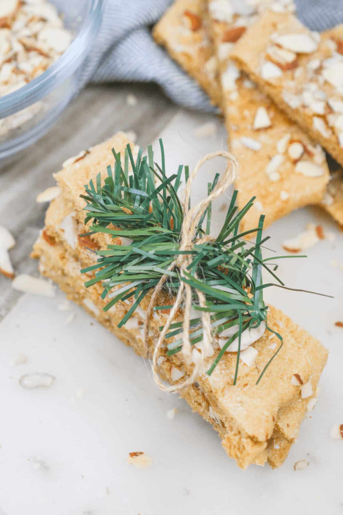 Dessert are wrapped with twine and adorned with a small pine twig, all elegantly placed on a white surface.