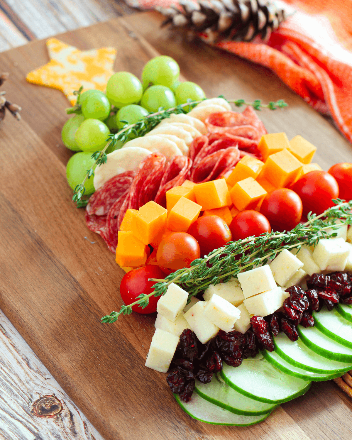 A cutting board with vegetables, meats and cheeses.