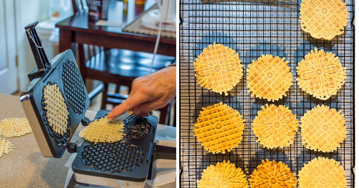 A hand removes a freshly cooked pizzelle cookie from a pizzelle maker; on the right, multiple pizzelle cookies cool on a wire rack.