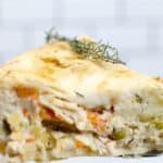 Close-up of a slice of Easy Turkey Pot Pie with a golden crust, packed with vegetables and tender turkey, garnished with a sprig of fresh thyme.