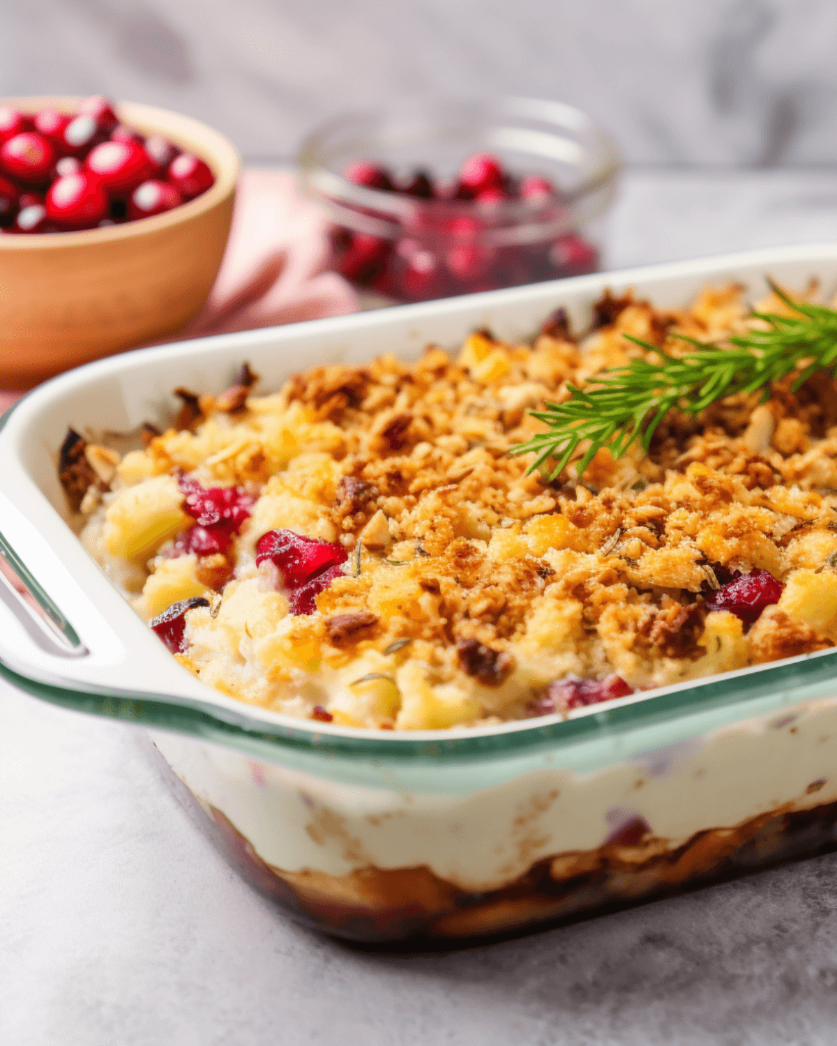 Leftover Thanksgiving casserole in a baking dish with cranberries in the background.  