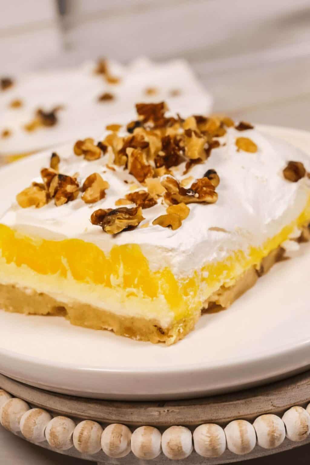 A square of lemon on a dish with nuts on top.