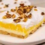 A square of lemon on a dish with nuts on top.