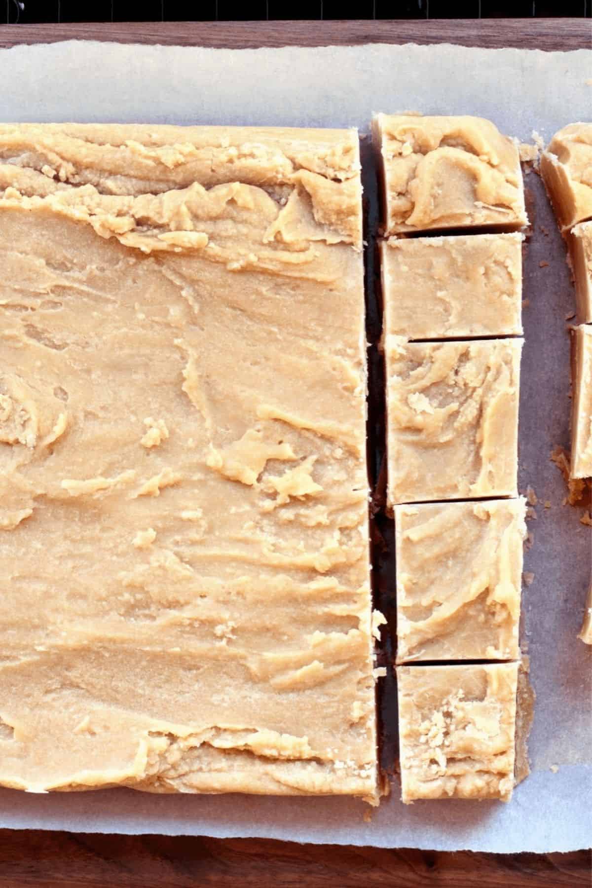 Candy partially sliced into rectangular pieces on a sheet of parchment paper.