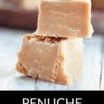 Two pieces of creamy penuche fudge stacked on a white surface, with more irresistible fudge blurred in the background.