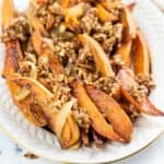 Wedges on a platter topped with chopped pecans and caramelized onions, with some pecan pieces scattered around.
