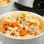 A white bowl filled with Slow Cooker Turkey Noodle Soup featuring tender turkey, egg noodles, and diced carrots.