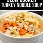 A white bowl filled with Slow Cooker Turkey Noodle Soup featuring shredded turkey, egg noodles, and chopped carrots, set on a striped cloth.