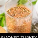 A glass jar filled with Smoked Turkey Dry Rub, a mixed blend of spices, sits labeled amidst fresh herbs and bowls in the background.