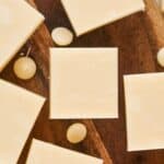 Squares of white chocolate and round pieces are arranged on a wooden surface, reminiscent of the creamy delights.