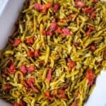 A white dish filled with Green Beans with Bacon and Onion, featuring tender green beans mixed with savory bacon pieces and caramelized onions.