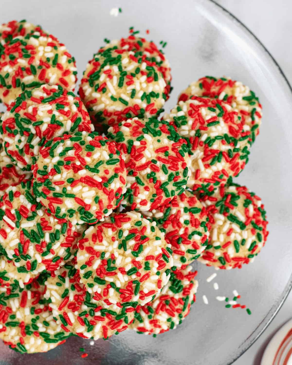 A pile of sprinkle cookies on a plate. 