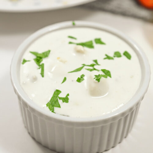 The best blue cheese dressing served in a white bowl, garnished with parsley.