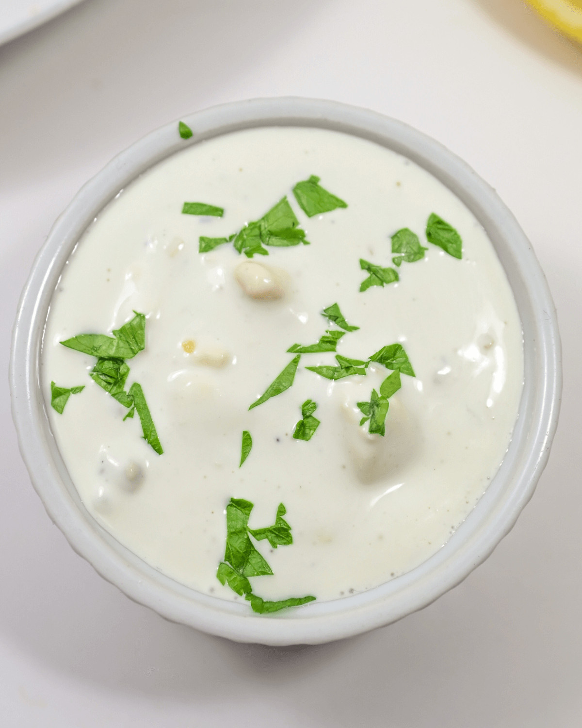 A bowl of the best blue cheese dressing with a hint of lemon and a garnish of fresh parsley.