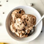 A bowl of cocoa condensed milk ice cream with marshmallows, chocolate chips, and condensed milk.