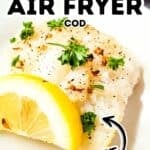 A fillet of Air Fryer Cod garnished with parsley, black pepper, and a lemon wedge on a white plate, with text overlay reading “Easiest Air Fryer Cod Perfect.”.