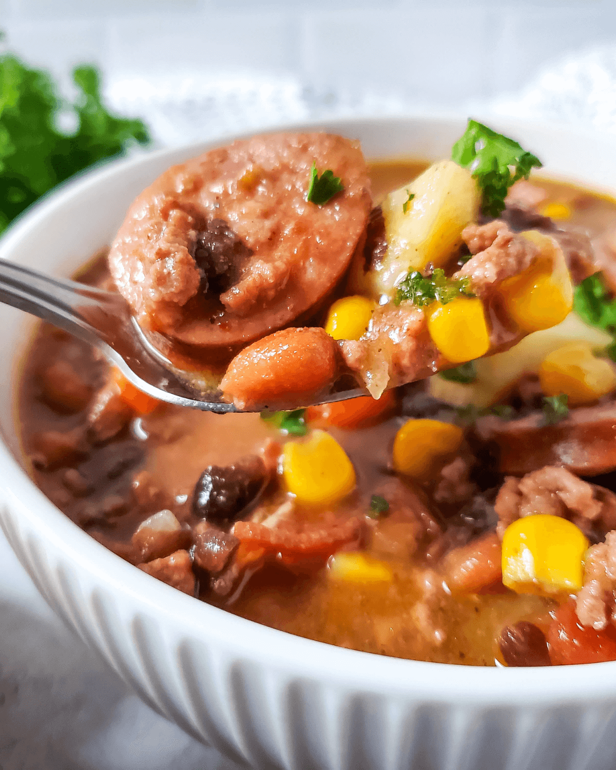 A spoonful with corn, beans, and sausage.