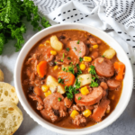 A bowl of cowboy stew with corn, beans and sausage.