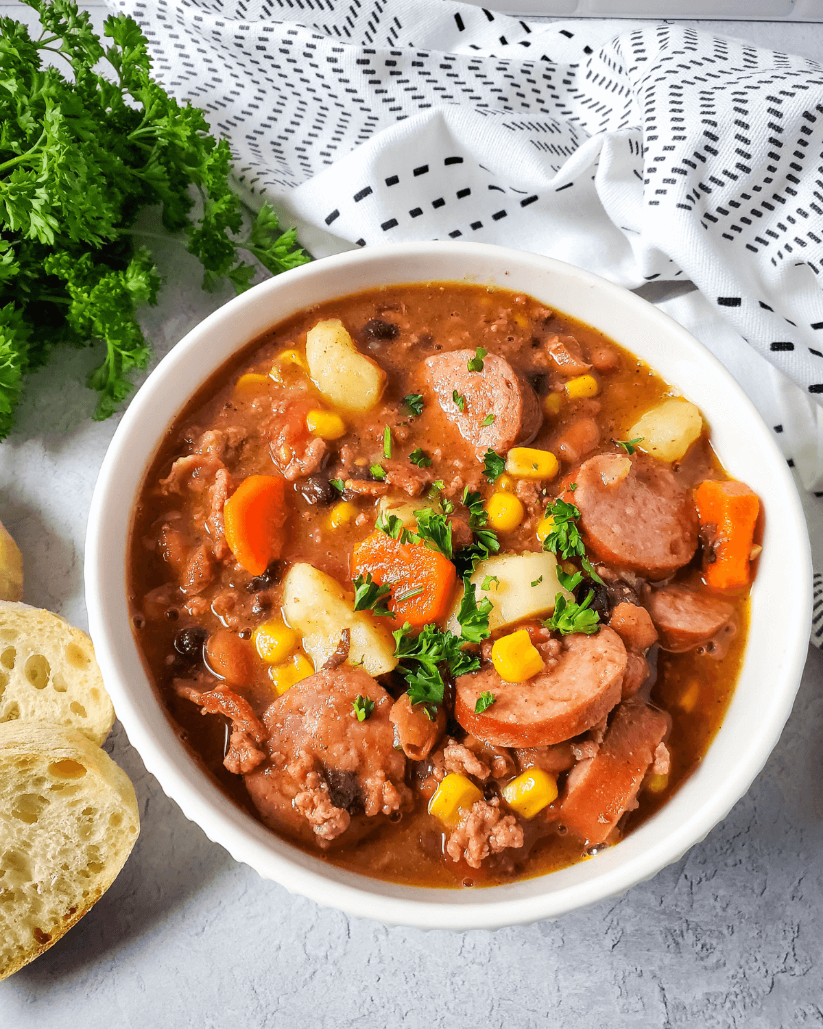 A bowl of cowboy stew with corn, beans and sausage.