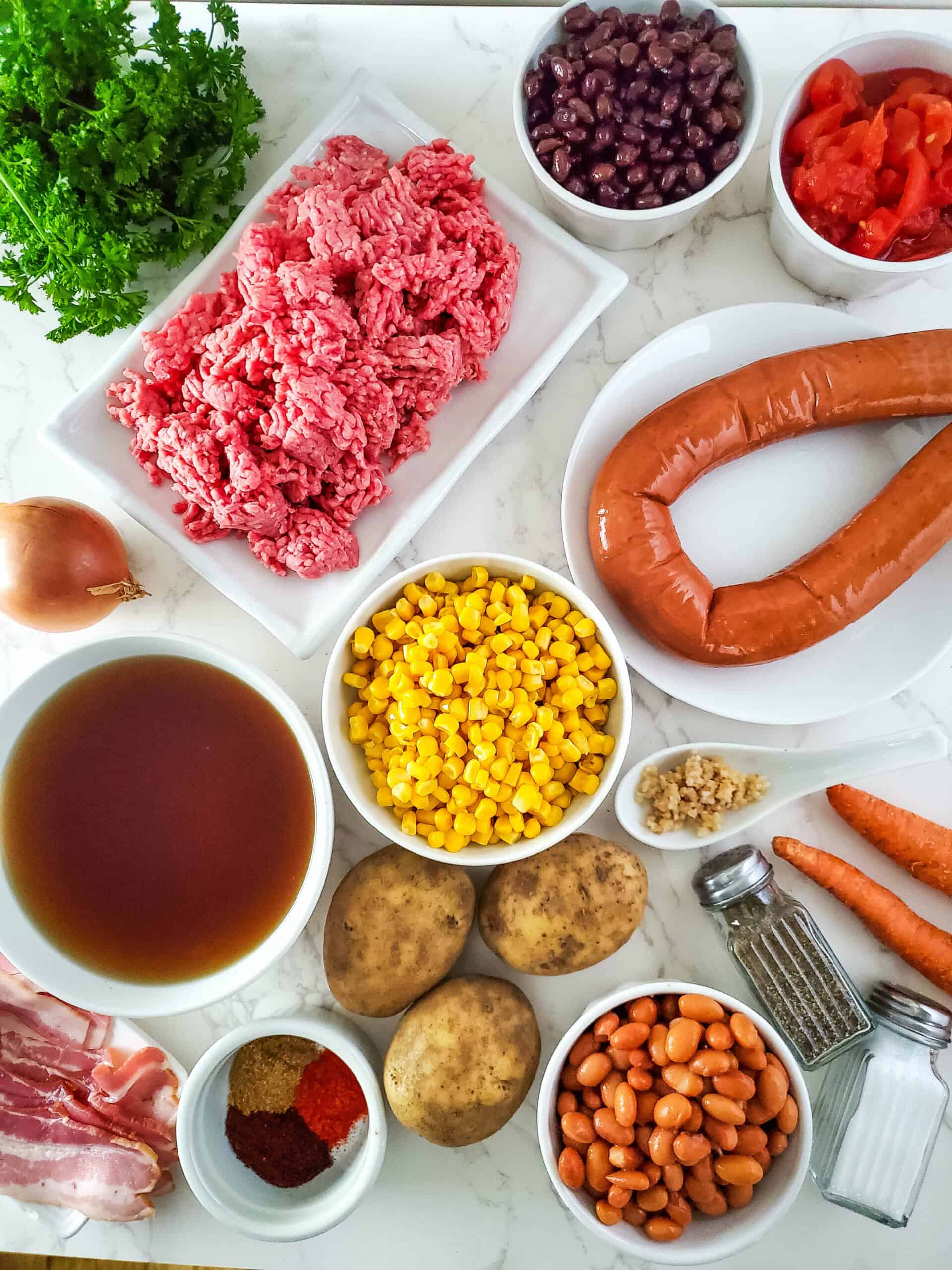 A plate of  sausage, beef, corn and potatoes to make the dinner.