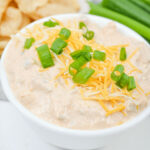 Cream cheese taco dip with chips and green onions.