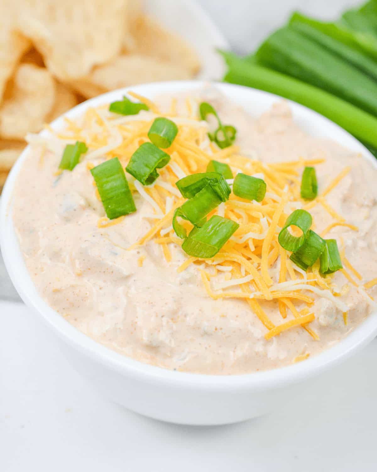 Cream cheese taco dip with chips and green onions.