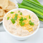 Cream Cheese Taco Dip with green onions, served alongside chips.