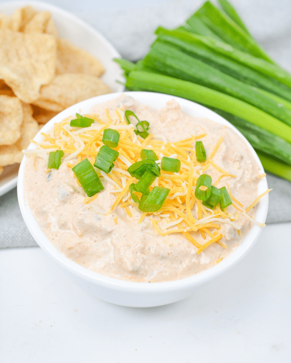 Cream Cheese Taco Dip with green onions, served alongside chips.