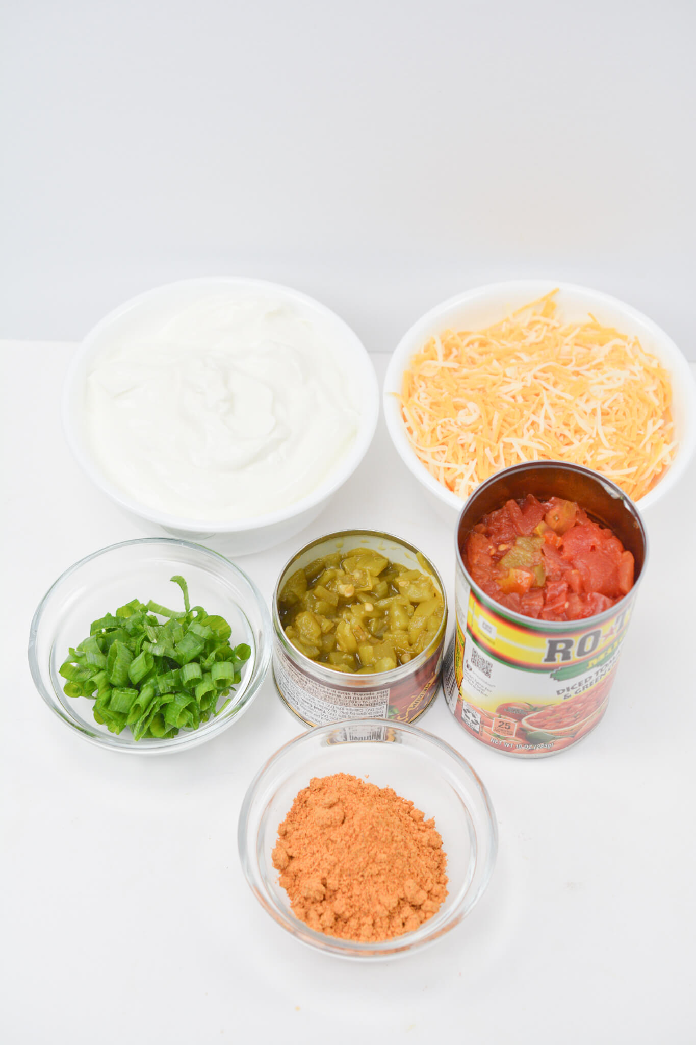 Ingredients for Mexican nachos topped with Cream Cheese Taco Dip (Boat Dip) on a white surface.
