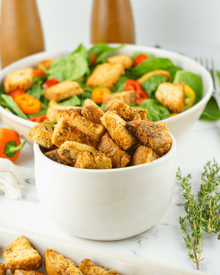 A bowl of homemade croutons atop a bed of fresh salad.