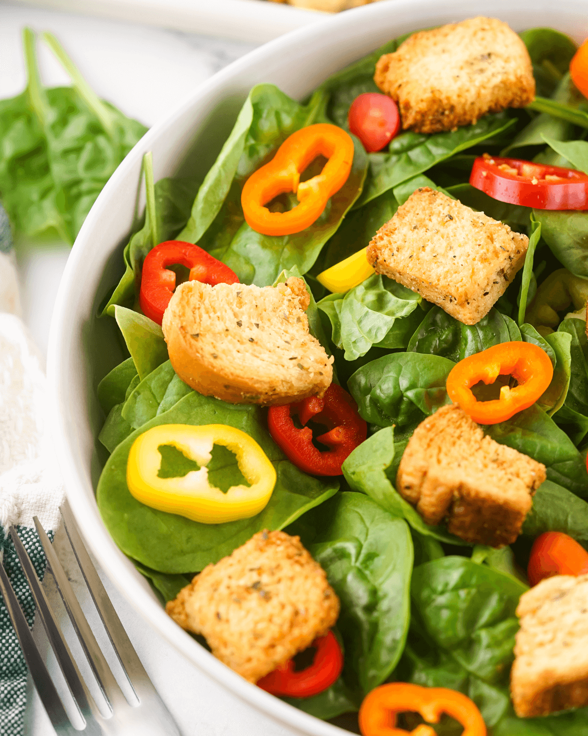 Spinach salad with homemade croutons and peppers.