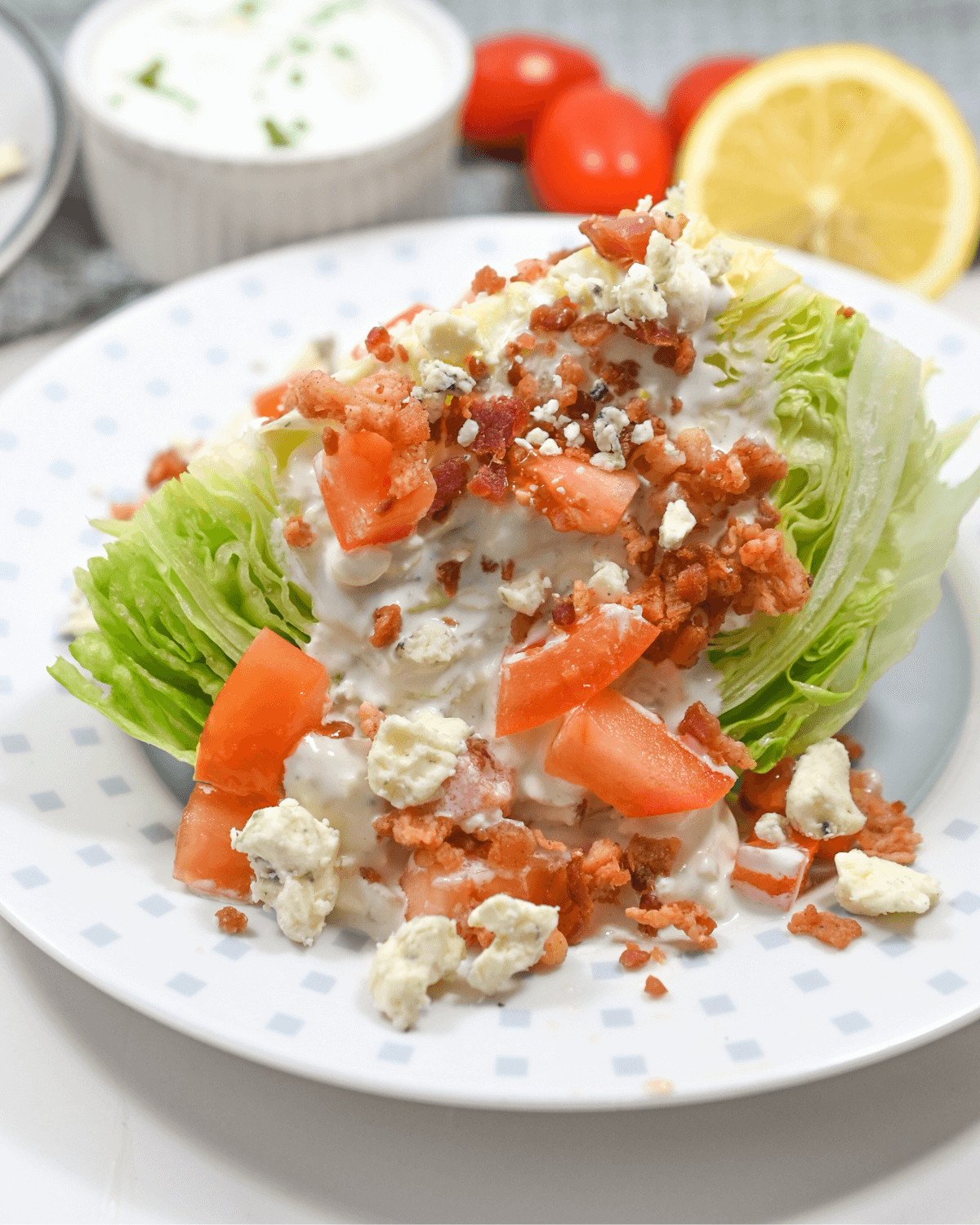 A plate with a wedge salad- lettuce, tomatoes and dressing on it.