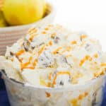 Apple Snickers Salad garnished with whipped cream served in a blue bowl.