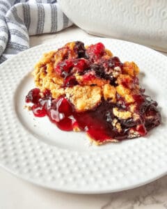 A blueberry cherry dump cake in a white plate.