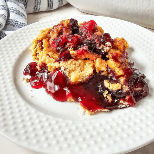A blueberry cherry dump cake in a white plate.
