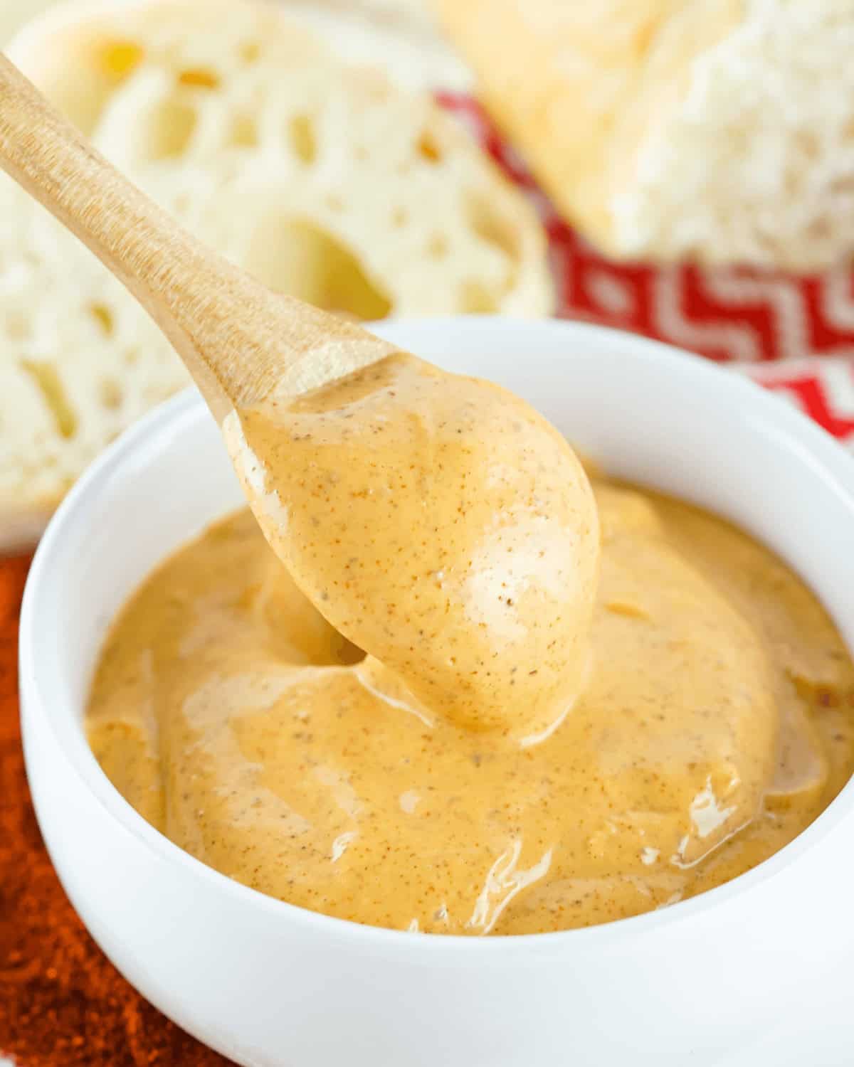 A white bowl with a spoon in it, filled with delicious Chipotle Mayo.