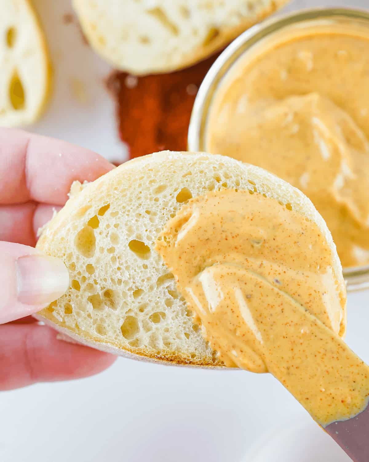 A person is dipping a spoon into a jar of Chipotle Mayo.