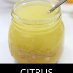 A jar of citrus vinaigrette with a spoon in it.