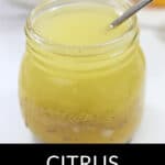 A jar of citrus vinaigrette with a spoon in it.