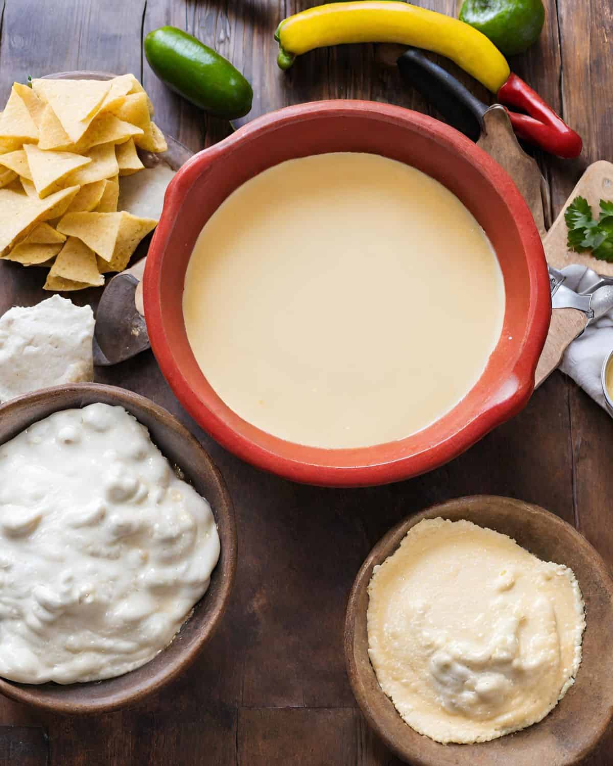 A bowl of guacamole accompanied by tortilla chips, all arranged on a rustic wooden table.