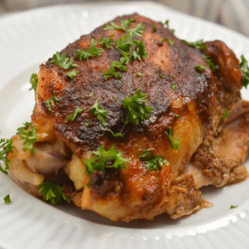 Crock pot BBQ Chicken with parsley garnish on a white plate.