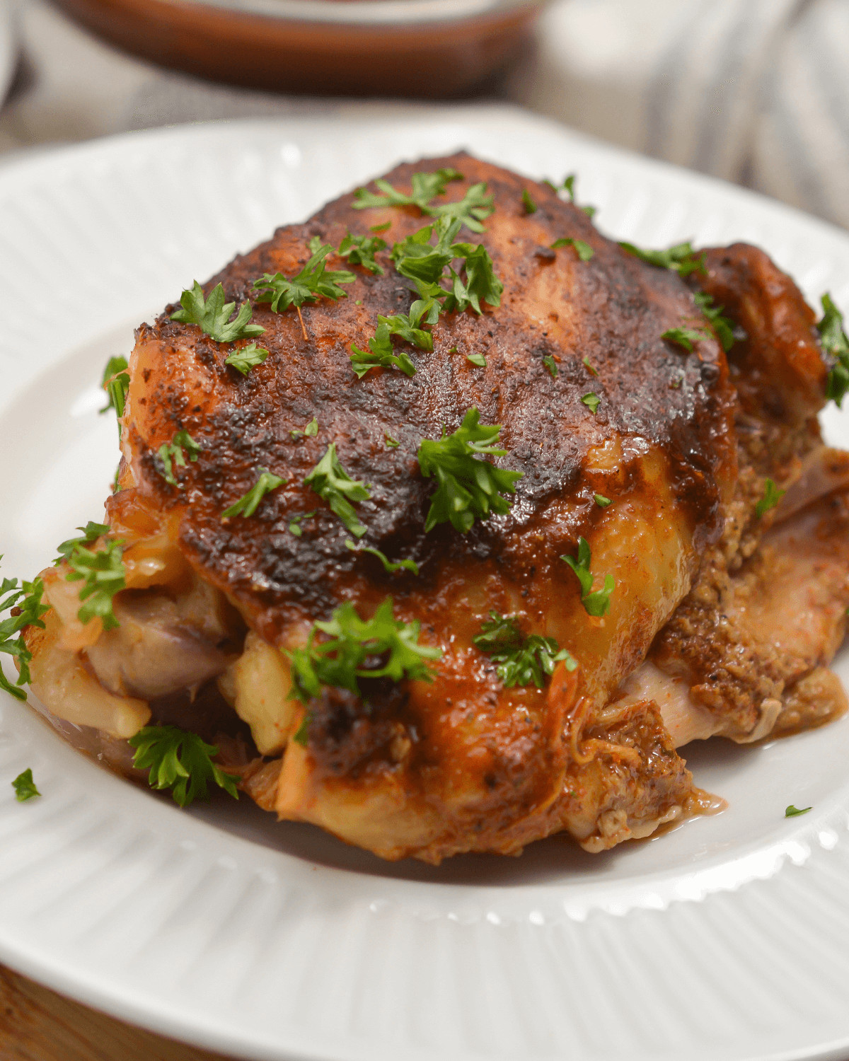 Crock pot BBQ Chicken with parsley garnish on a white plate.