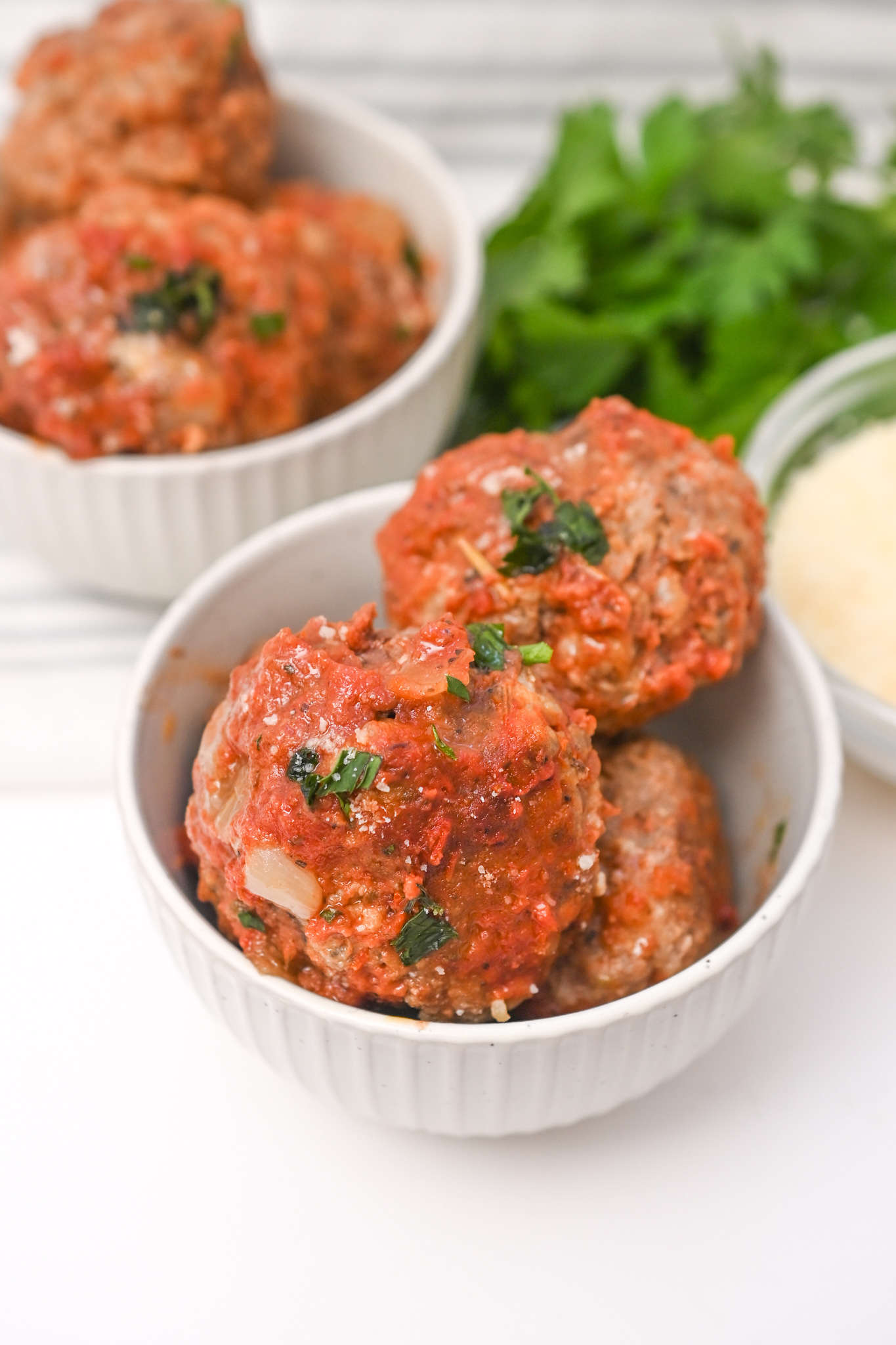A bowl of Italian sausage meatballs with sauce and parmesan.