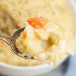 A spoon is holding a bowl of Easy Crock Pot Chicken and Dumplings.