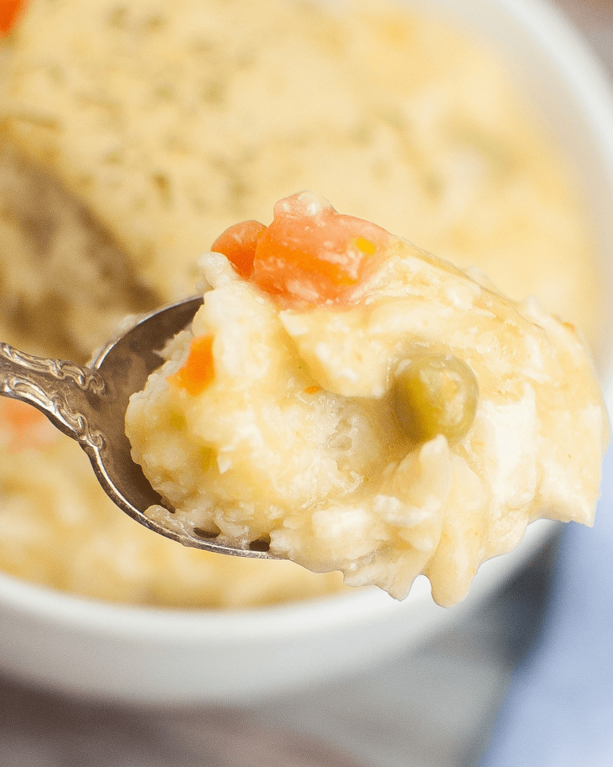 A spoon is holding a bowl of Easy Crock Pot Chicken and Dumplings.