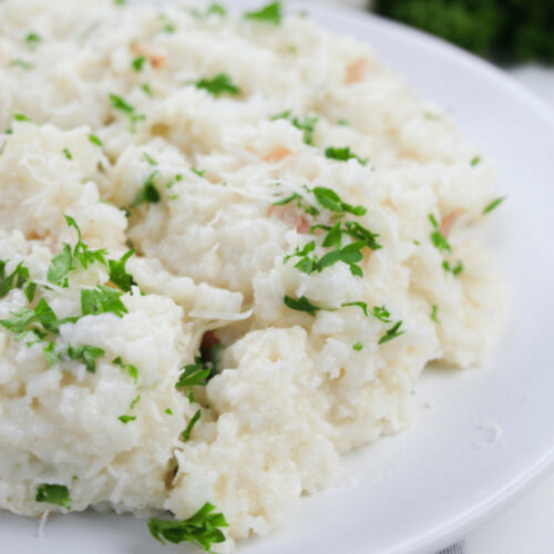 Creamy lemony shrimp risotto served on a white plate, garnished with parsley.