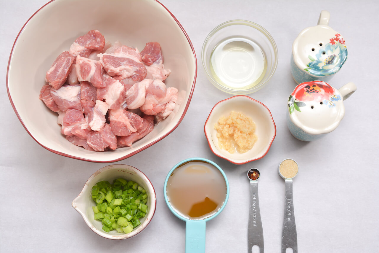 A bowl with ingredients such as pork, honey, and seasonings for the dish.